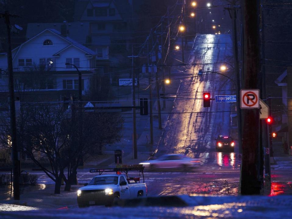 Cars try to climb the frozen hills on 28th street at Ingersoll Ave. on Monday, Jan. 16, 2017, in Des Moines, Iowa. Travel remains hazardous in parts of Iowa and Nebraska as ice storms move north and east through the states. (Brian Powers/The Des Moines Register via AP )