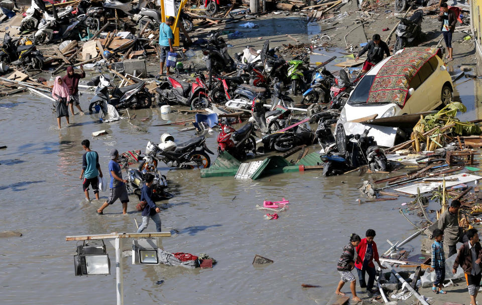 In this Sunday, Sept. 30, 2018, file photo, people survey outside the flooded shopping mall which was damaged following earthquakes and a tsunami in Palu, Central Sulawesi, Indonesia. (AP Photo/Tatan Syuflana, File)