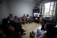 Family members of Ghassan Hasrouty, a missing silo employee, watch a news channel on television as they wait for information, following Tuesday's blast in Beirut's port area