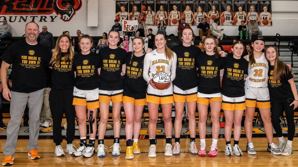 Harbor Springs junior Olivia Flynn (middle, 23) holds a special commemorative ball, as teammates and coaches show off their special shirts, after Flynn became the program's all-time leader in points scored last week.