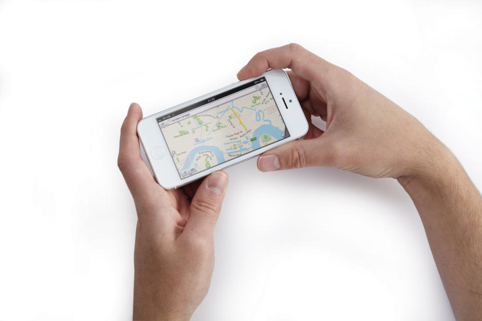 (EDITORS NOTE: This image has been digitally manipulated) A close-up of a man's hands using a white Apple iPhone 5 smartphone to view maps, taken on October 24, 2012. (Photo by Joseph Branston/Apple Bookazine via Getty Images)