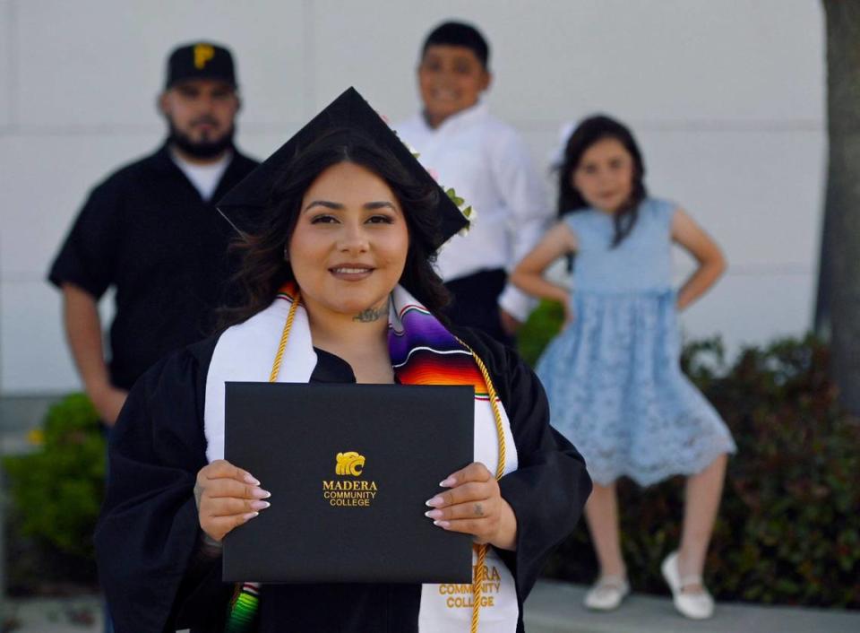 La graduada del Madera Community College Vanessa Barraza, con su familia al fondo: su esposo José Barraza, izquierda; su hijo Julio Barraza, de 10 años, centro, y su hija Lailani Barraza, de 7, derecha. Fotografiados el martes 28 de mayo de 2024, en Madera.