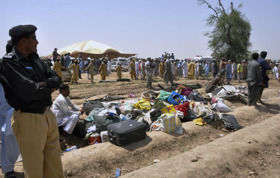 A police officer and volunteers gather at the site of a train collision in Ghotki district in the southern Pakistan, Monday, June 7, 2021. Two express trains collided in southern Pakistan early Monday, killing dozens of passengers, authorities said, as rescuers and villagers worked to pull injured people and more bodies from the wreckage. (AP Photo/Waleed Saddique)