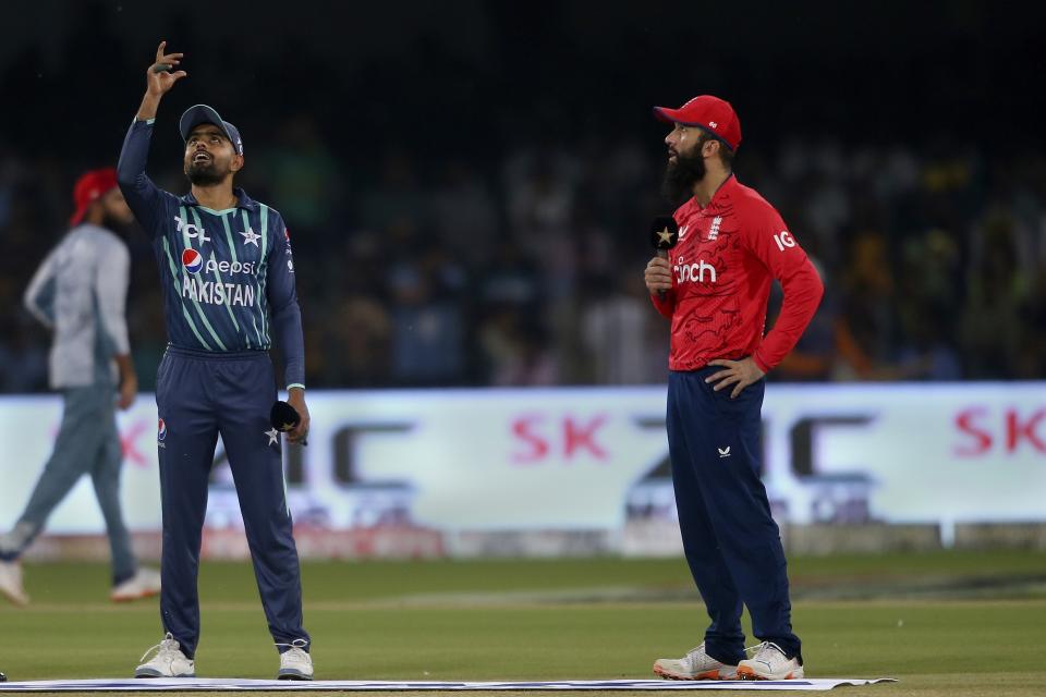 Pakistan's skipper Babar Azam, left, spins the coin as his England's counterpart Moeen Ali watches during toss for the seventh twenty20 cricket match between Pakistan and England, in Lahore, Pakistan, Sunday, Oct. 2, 2022. (AP Photo/K.M. Chaudary)