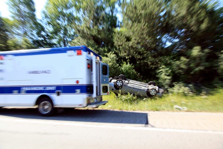 Ambulance speeding by a gray car flipped over