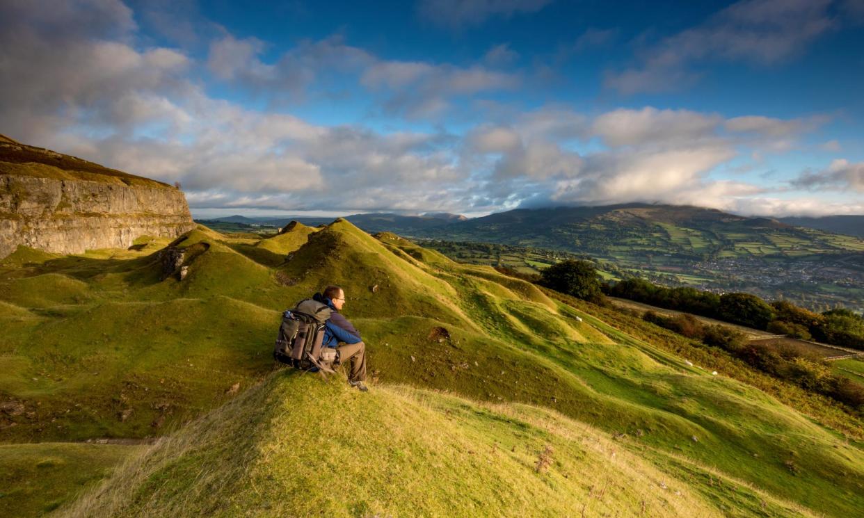 <span>A hiker takes in the view in the Llangattock escarpment quarries looking towards Crickhowell, Wales.</span><span>Photograph: Michael Roberts/Getty Images</span>