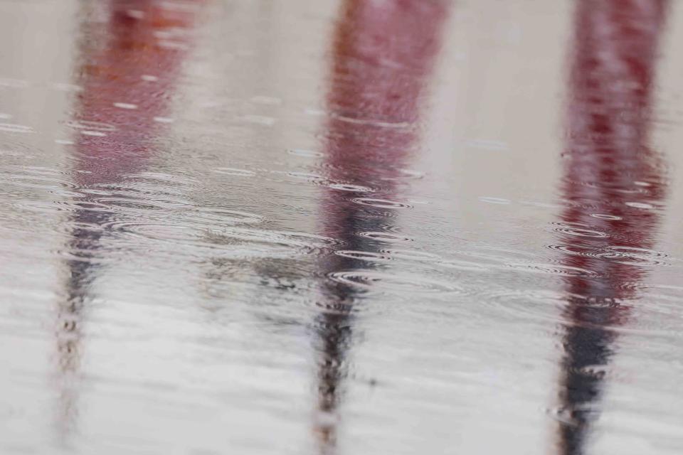 A reflection of three American flags as rain falls on a pool of water during traditional Memorial Day Ceremony Sunday, May 30, 2021, at Veterans Memorial Park in New Castle.