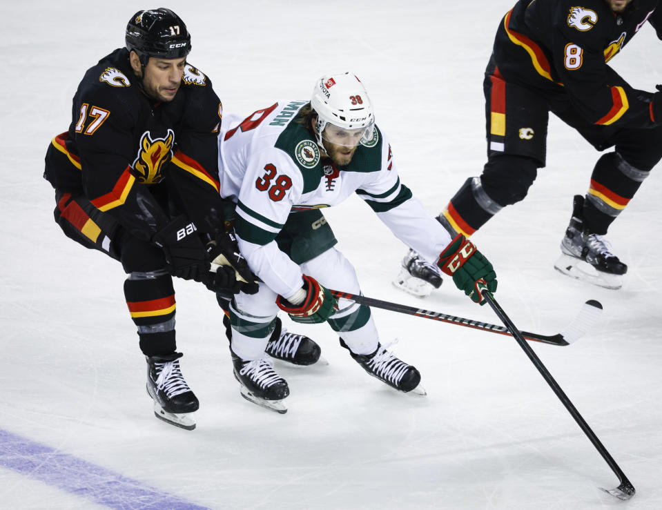 Minnesota Wild forward Ryan Hartman, right, is checked by Calgary Flames forward Milan Lucic during the first period of an NHL hockey game Saturday, March 4, 2023, in Calgary, Alberta. (Jeff McIntosh/The Canadian Press via AP)