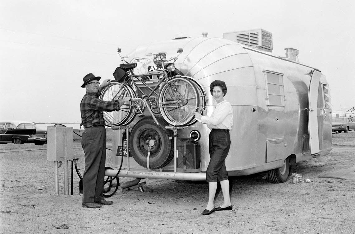 Airstream Travel Trailer owner demonstrates how to transport two bicycles along with his trailer. This is at the Airstream Rally on Coquina Beach in 1965.