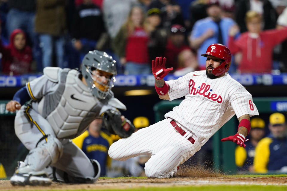 Philadelphia Phillies' Nick Castellanos, right, scores past Milwaukee Brewers catcher Victor Caratini on a two-run single by Alec Bohm during the eighth inning of a baseball game, Friday, April 22, 2022, in Philadelphia. (AP Photo/Matt Slocum)