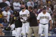 San Diego Padres' Fernando Tatis Jr., center, is helped off the field by manager Jayce Tingler, left, and a trainer during the first inning the team's baseball game against the Colorado Rockies, Friday, July 30, 2021, in San Diego. (AP Photo/Derrick Tuskan)