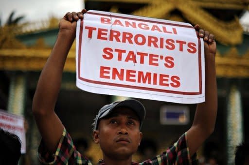 An ethnic Rakhine demonstrator holds a sign as hundreds protest at Yangon's Shwedagon pagoda after unrest flared in the western Myanmar state. Security forces have tried to restore order to a Myanmar state placed under emergency rule after a wave of deadly religious violence, as the United Nations evacuated foreign workers