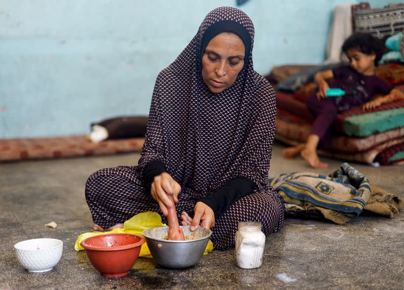 FILE PHOTO: A displaced Palestinian woman prepares food at a school classroom where she shelters, amid food scarcity, as Israel-Hamas conflict continues, in Khan Younis in the southern Gaza Strip