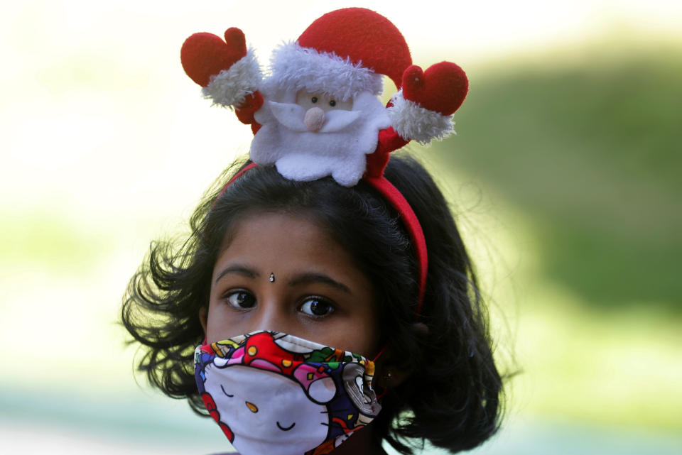 A Sri Lankan Christian girl wears a Santa hair band and a face mask as a precaution against the coronavirus as she arrives at a church to attend the Christmas mass in Colombo, Sri Lanka, Friday, Dec. 25, 2020. (AP Photo/Eranga Jayawardena)