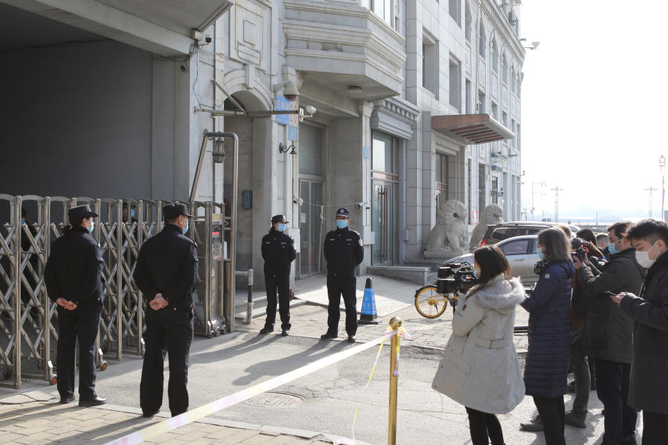 Journalists film as security officers stand guard at an entrance to a court building in Dandong in northeastern China's Liaoning Province, Friday, March 19, 2021. China was expected to open the first trial Friday for Michael Spavor, one of two Canadians who have been held for more than two years in apparent retaliation for Canada's arrest of a senior Chinese telecom executive. (AP Photo/Ken Moritsugu)
