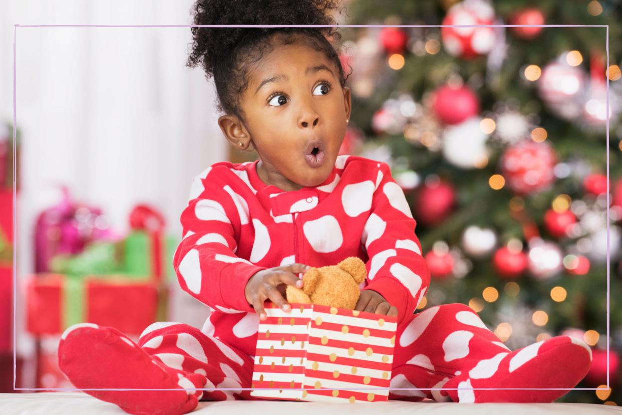  Child opening Christmas present to find a bear. 