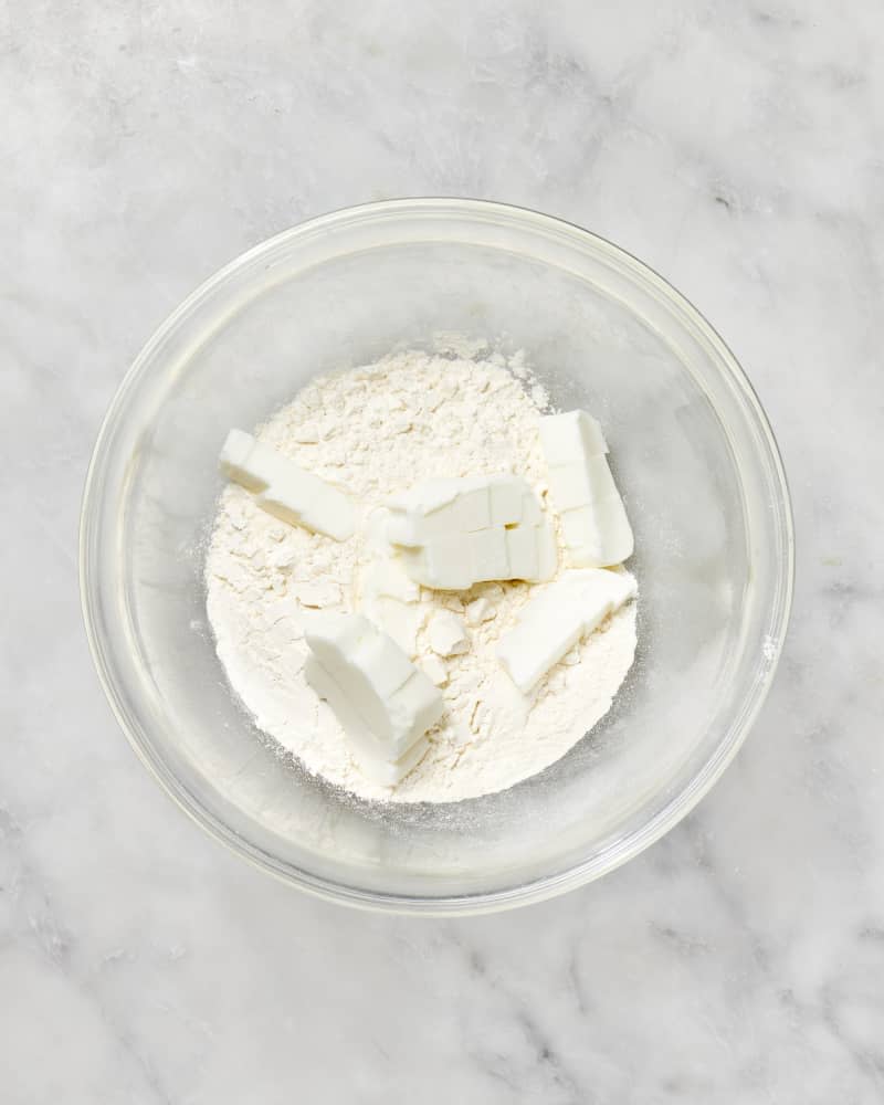 A bowl with flour and cubes of shortening to make a pie crust seen from above.