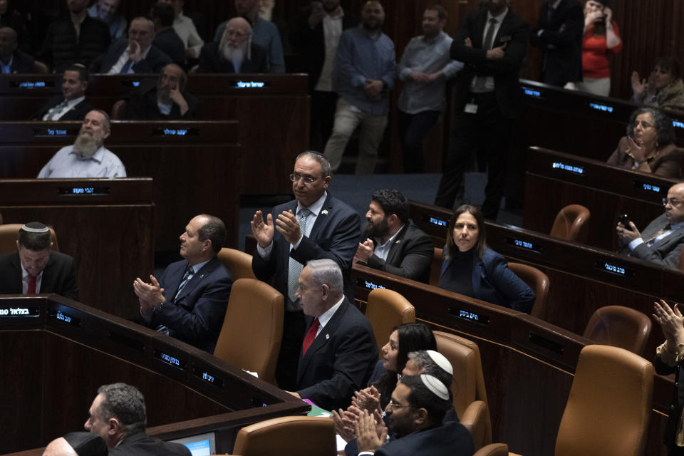 Israeli Prime Minister Benjamin Netanyahu, center, is surrounded by lawmakers at Israel's parliament, the Knesset, during a vote on a contentious plan to overhaul the country's legal system, in Jerusalem, early Tuesday, Feb. 21, 2023. (AP Photo/Maya Alleruzzo, Pool)