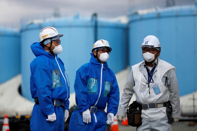 FILE PHOTO: Workers are seen in front of storage tanks for radioactive water are seen at tsunami-crippled Fukushima Daiichi nuclear power plant in Okuma town, Fukushima prefecture