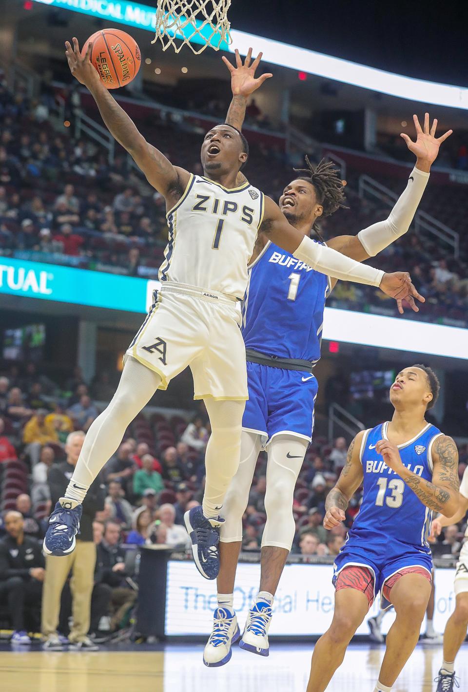 Akron’s Garvin Clarke drives past Buffalo’s LaQuill Hardnett for a first-half basket in a MAC quarterfinal Thursday at Rocket Mortgage Fieldhouse.