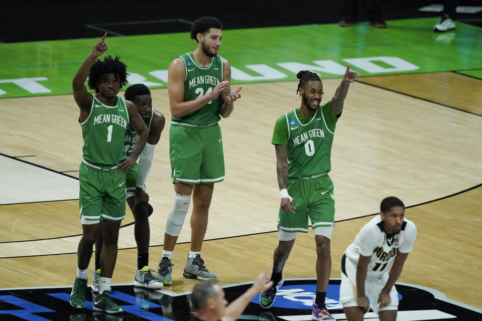 North Texas's Mardrez McBride, Thomas Bell (13), Zachary Simmons (24) and James Reese (0) react as Javion Hamlet shoots free throws during overtime of a first-round game against Purdue in the NCAA men's college basketball tournament at Lucas Oil Stadium, Friday, March 19, 2021, in Indianapolis. North Texas defeated Purdue 78-69 in overtime. (AP Photo/Darron Cummings)