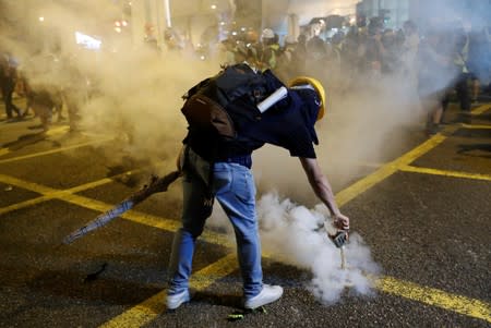 An anti-extradition demonstrator puts down a smoke cake in front of Chinese Liaison Office, after a march of to call for democratic reforms, in Hong Kong