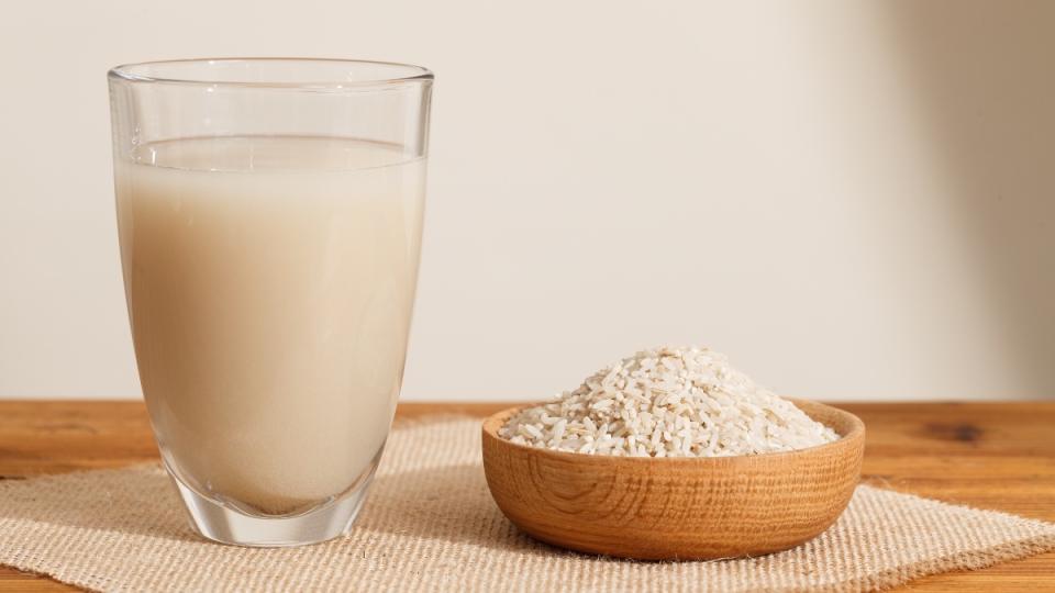 A cup of rice water next to a bowl of rice, which can ease diarrhea