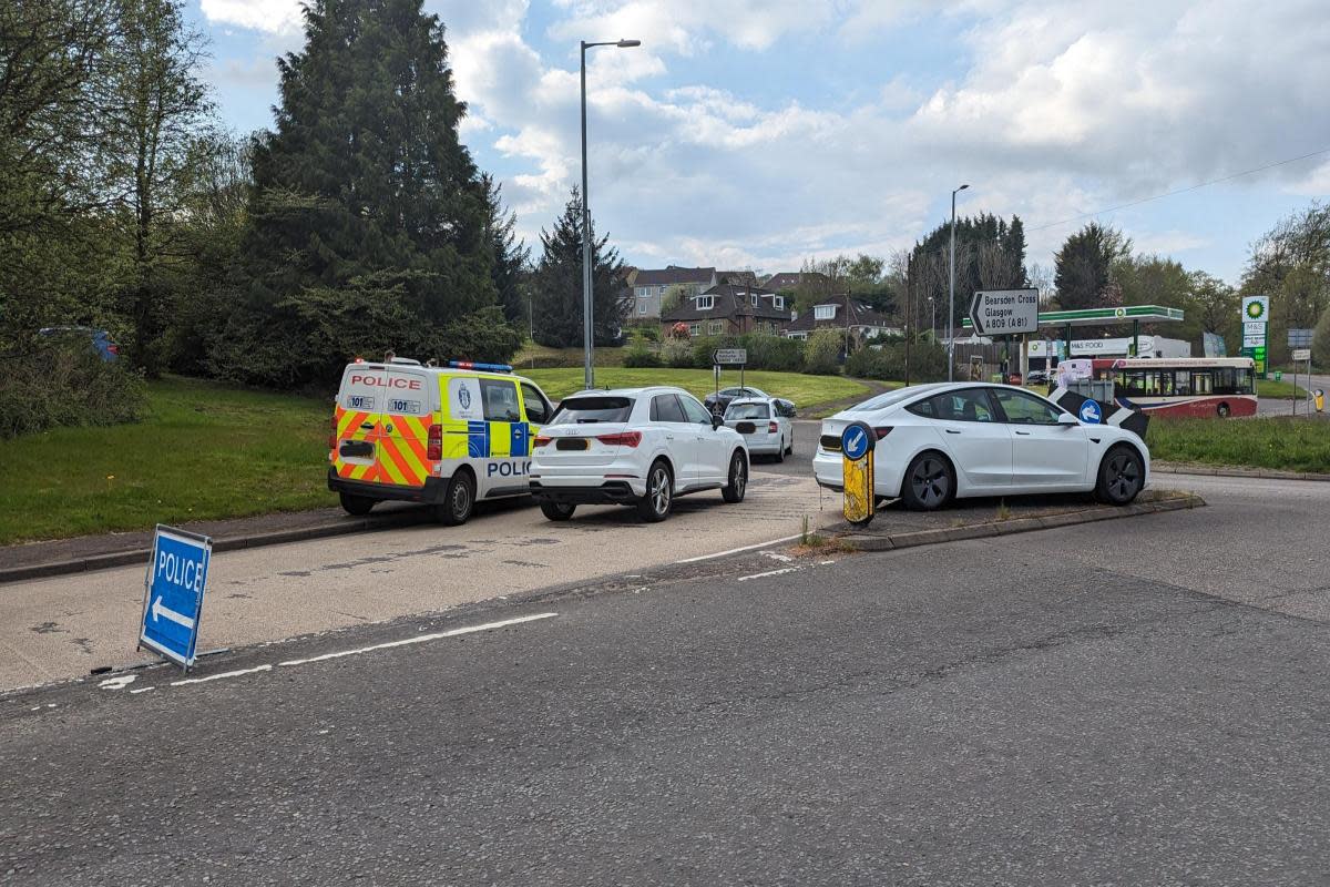 A car passes along the reopened road between the police vehicle and a white vehicle stranded on a traffic island following the incident <i>(Image: Newsquest)</i>