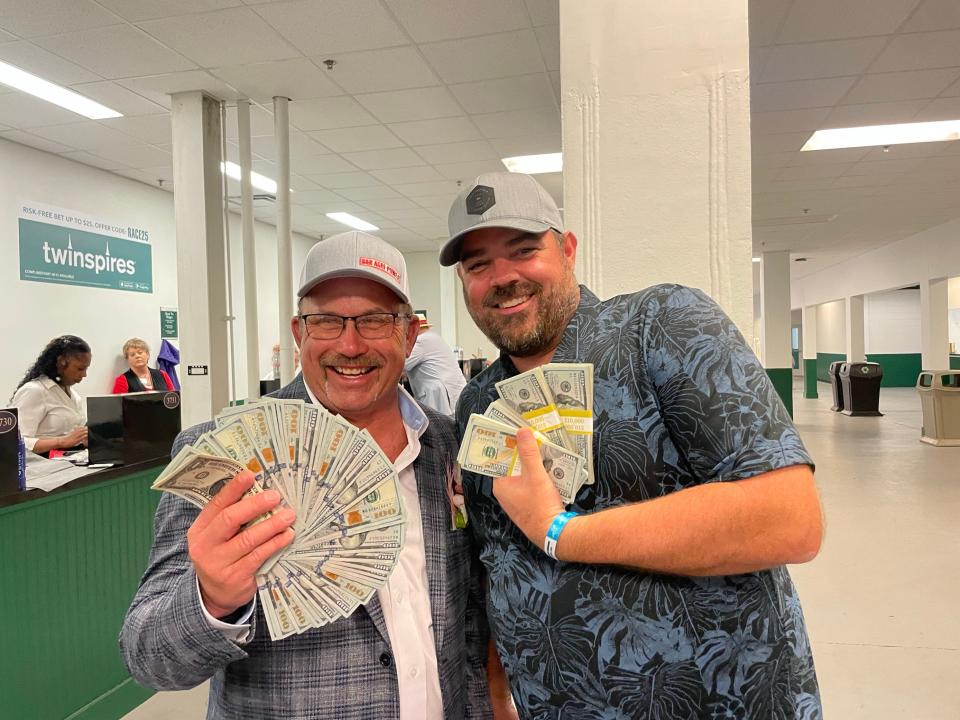 Craig Gough (left) and Dave Oblisk (right) show their winnings after betting on the 150th running of the Kentucky Derby.