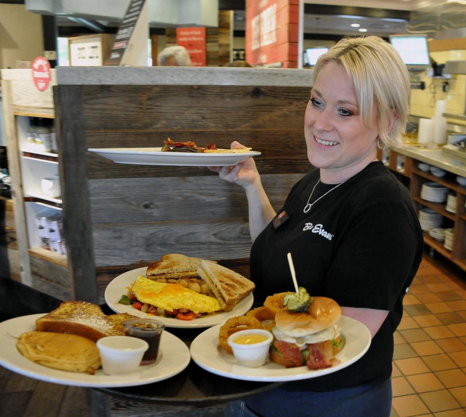 Bob Evans server Chevaun Pannell delivers several meals to a customer at a Wooster Bob Evans Restaurant. They will be open on Thanksgiving Day.