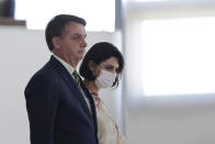 Brazil's President Jair Bolsonaro and his wife Michelle Bolsonaro wearing a protective face mask, arrive for a swearing ceremony for his new justice minister, at the Planalto presidential palace, in Brasilia, Brazil, Wednesday, April 29, 2020. (AP Photo/Eraldo Peres)