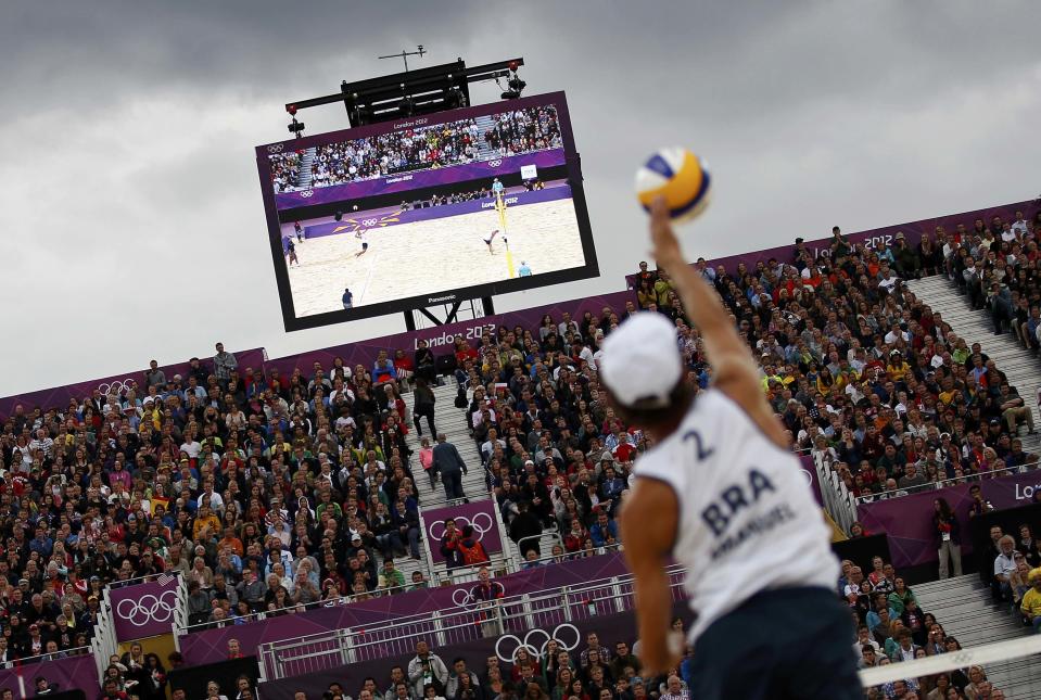 Spectators watch as Brazil's Emanuel serves against Poland's Mariusz Prudel and Grzegorz Fijalek during their men's quarterfinals beach volleyball match at Horse Guards Parade during the London 2012 Olympic Games August 6, 2012. REUTERS/Marcelo Del Pozo (BRITAIN - Tags: OLYMPICS SPORT VOLLEYBALL TPX IMAGES OF THE DAY) 