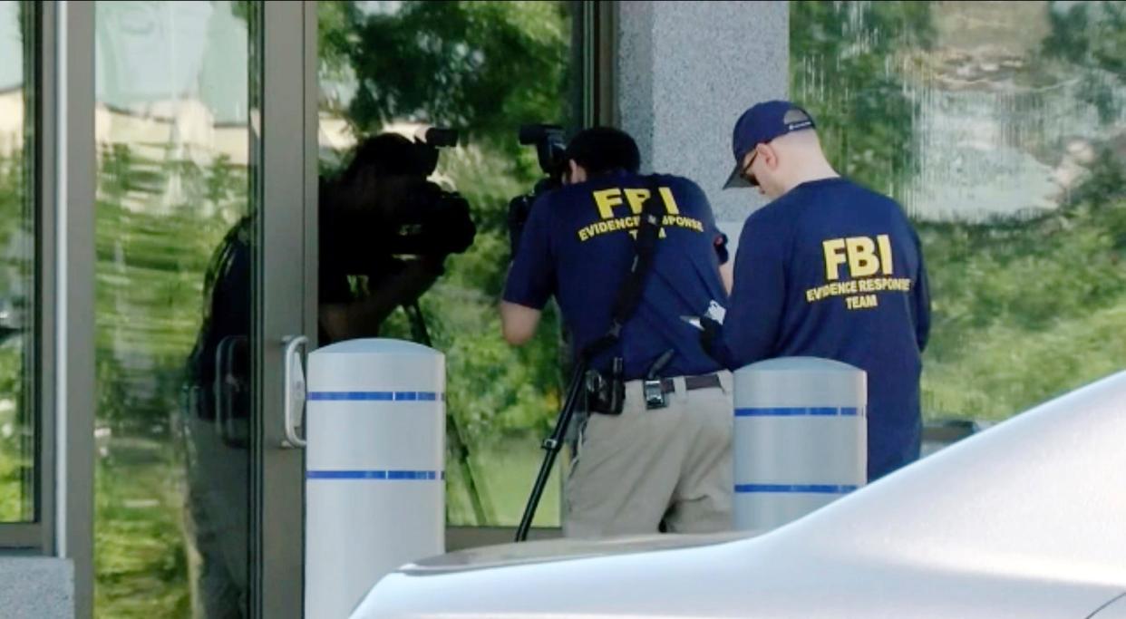 In this still image taken from WKEF/WRGT video, members of the FBI Evidence Response Team work outside the FBI building in Kenwood, Ohio, on Thursday, Aug. 11, 2022. An armed man decked out in body armor tried to breach a security screening area.