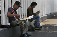 Men eat a meal from the mobile dining rooms program as people who have not been able to work because of the COVID-19 pandemic line up for a meal outside the Iztapalapa hospital in Mexico City, Wednesday, May 20, 2020. (AP Photo/Marco Ugarte)