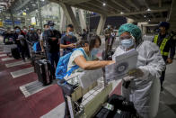 A public health worker screens Chinese tourists from Shanghai who arrived at Suvarnabhumi airport on a "Special Tourist Visa, in Bangkok, Thailand, Tuesday, Oct 20, 2020. Thailand on Tuesday took a modest step toward reviving its coronavirus-battered tourist industry by welcoming 39 visitors who flew in from Shanghai, the first such arrival since normal traveler arrivals were banned almost seven months ago. (AP Photo/Wason Wanichakorn)