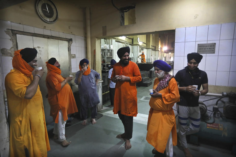 Sikh volunteers take a tea break in the kitchen hall of the Bangla Sahib Gurdwara in New Delhi, India, Sunday, May 10, 2020. The Bangla Sahib Gurdwara has remained open through wars and plagues, serving thousands of people simple vegetarian food. During India's ongoing coronavirus lockdown about four dozen men have kept the temple's kitchen open, cooking up to 100,000 meals a day that the New Delhi government distributes at shelters and drop-off points throughout the city. (AP Photo/Manish Swarup)