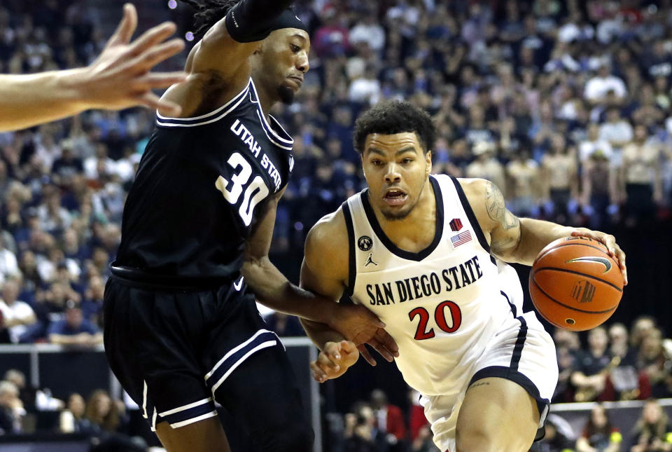 San Diego State guard Matt Bradley (20) drives past Utah State forward Dan Akin (30) during the first half of an NCAA college basketball game for the men's Mountain West Tournament championship Saturday, March 11, 2023, in Las Vegas. (AP Photo/Steve Marcus)