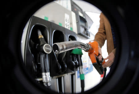 FILE PHOTO: A man holds a fuel nozzle at a Carrefour hypermarket petrol station in Nice, France, November 8, 2018. Picture taken with a fisheye lens. REUTERS/Eric Gaillard/File Photo