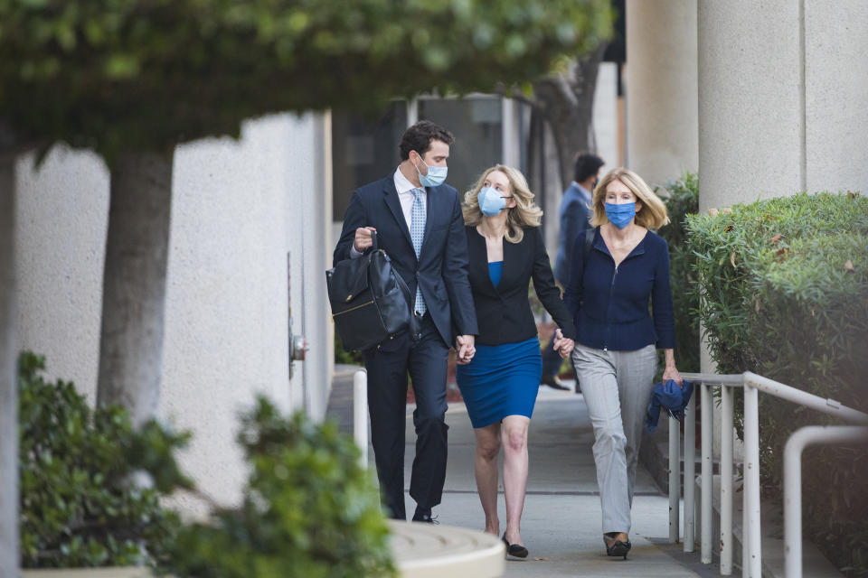 Elizabeth Holmes, center, looks at her partner Billy Evans, left, as they walk into federal court in San Jose, Calif., Monday, Nov. 22, 2021. Holmes is accused of duping elite financial backers, customers and patients into believing that her startup was about to revolutionize medicine. (AP Photo/Nic Coury)