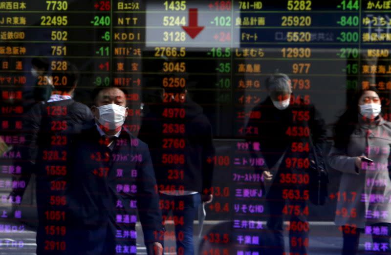 Pedestrians are reflected in an electronic board displaying various stock prices at a brokerage in Tokyo