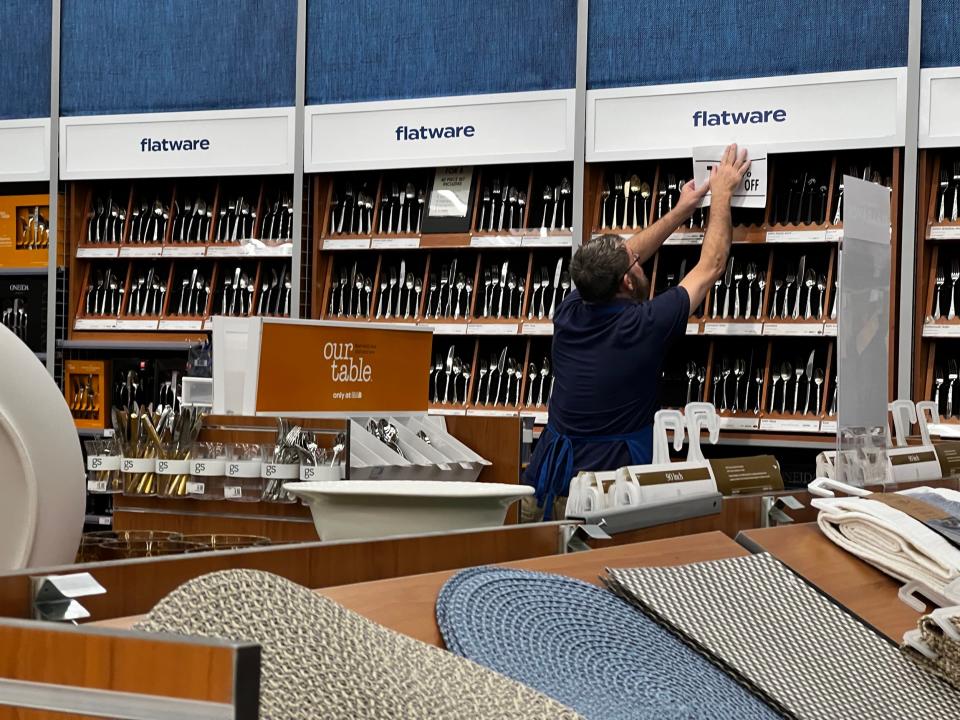 An employee hangs discount signage at a Bed Bath & Beyond store