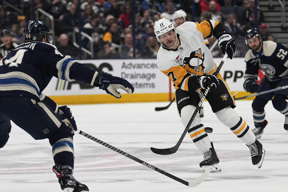 Pittsburgh Penguins right wing Bryan Rust (17) passes the puck between Columbus Blue Jackets' Erik Gudbranson (44) and Emil Bemstrom (52) during the first period of an NHL hockey game Tuesday, Nov. 14, 2023, in Columbus, Ohio. (AP Photo/Sue Ogrocki)