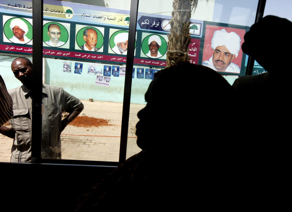 FILE - In this April 10, 2010 file photo, Sudanese women looks through a bus window as it passes posters supporting then Sudanese President and presidential candidate Omar al-Bashir, right, and his ruling National Congress Party candidates, in Khartoum, Sudan. Activists are calling for mass protests in the capital, Khartoum, and elsewhere across the country to demand the disbanding of the National Congress Party. The Sudanese Professionals' Association, which spearheaded the uprising against Bashir's rule, said the protests Monday, Oct. 21, 2019, will also renew demands to step up an independent investigation into the deadly break-up of protests in June. (AP Photo/Amr Nabil, File)