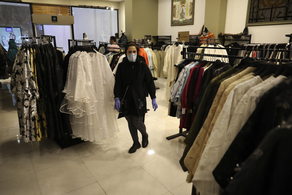 A woman wearing a face mask walks through a store in Bamland shopping mall, in Western Tehran, Iran, Sunday, March 15, 2020. Many people in Tehran shrugged off warnings over the new coronavirus as authorities complained that most people in the capital are not treating the crisis seriously enough. (AP Photo/Vahid Salemi)