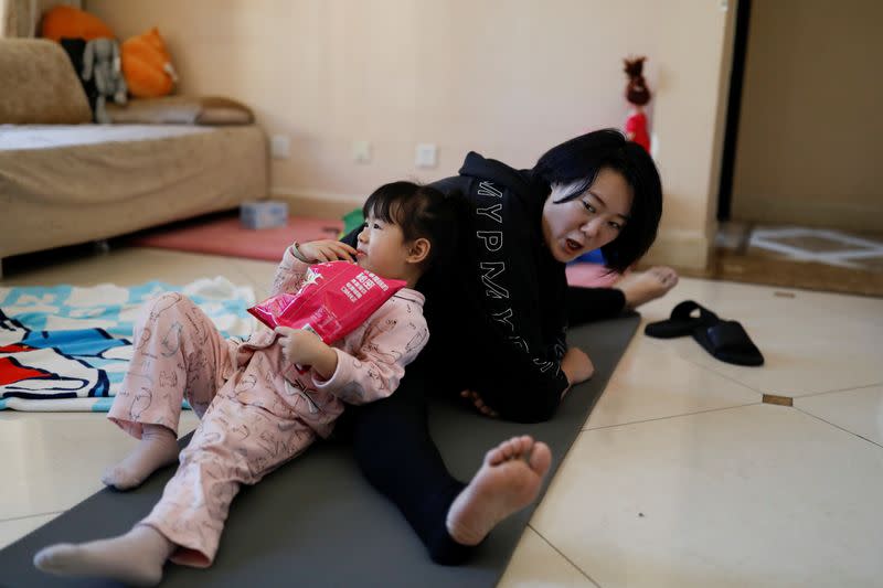 Zhang Kefei speaks to her daughter Cai, as she follows an exercise class being livestreamed, at their house, as the country is hit by an outbreak of the new coronavirus, in Beijing