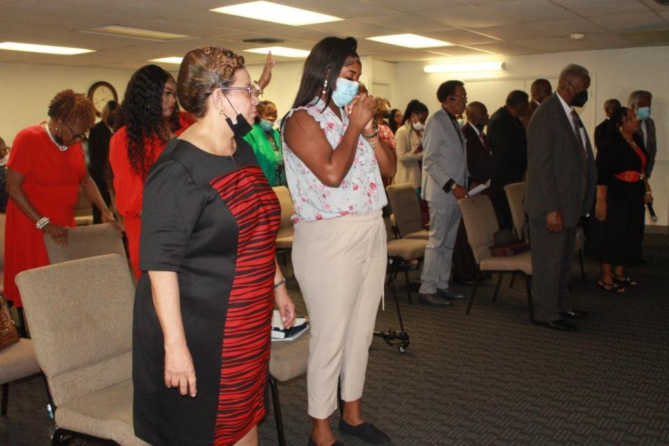 Parishioners stand in prayer Sunday during a service at Victorious Life International celebrating the 11th anniversary of Apostle Tanaka Gates as founder and pastor of the church.