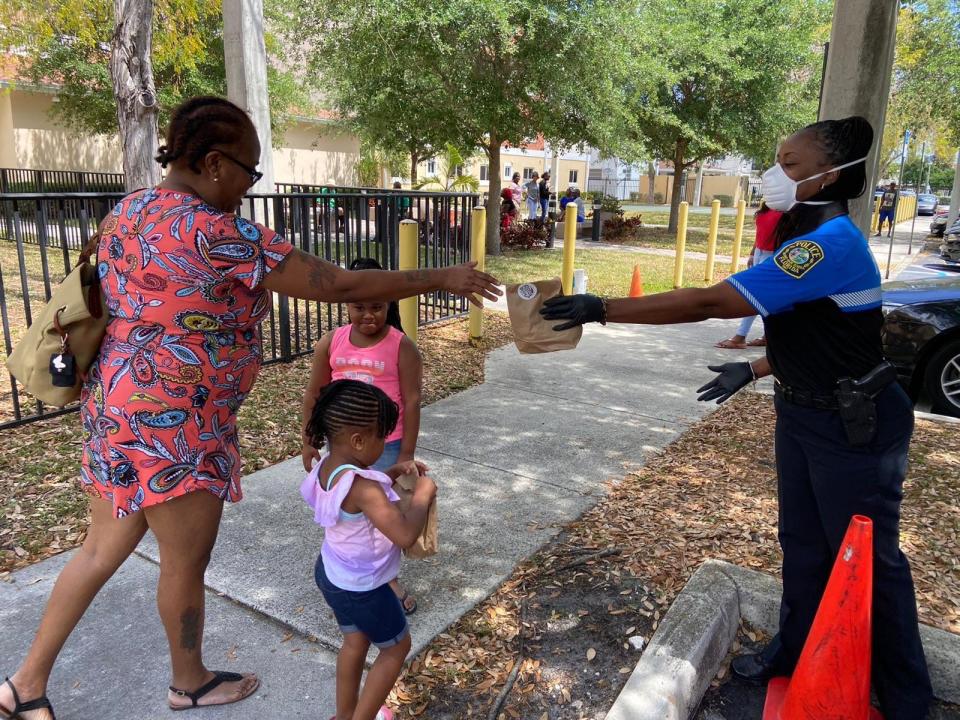 A mother picks up grab-and-go free meals distributed by the Miami-Dade Schools Police Department together with Miami-Dade County Public Schools during school closures.