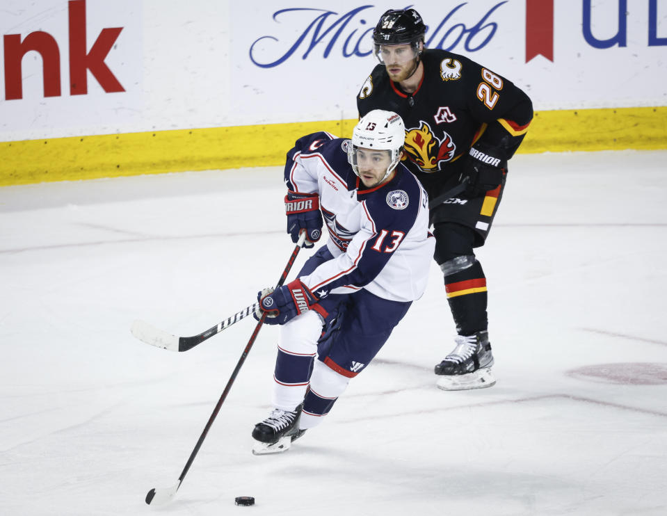 Columbus Blue Jackets forward Johnny Gaudreau (13) steals the puck from Calgary Flames forward Elias Lindholm (28) during the second period of an NHL hockey game Thursday, Jan. 25, 2024, in Calgary, Alberta. (Jeff McIntosh/The Canadian Press via AP)