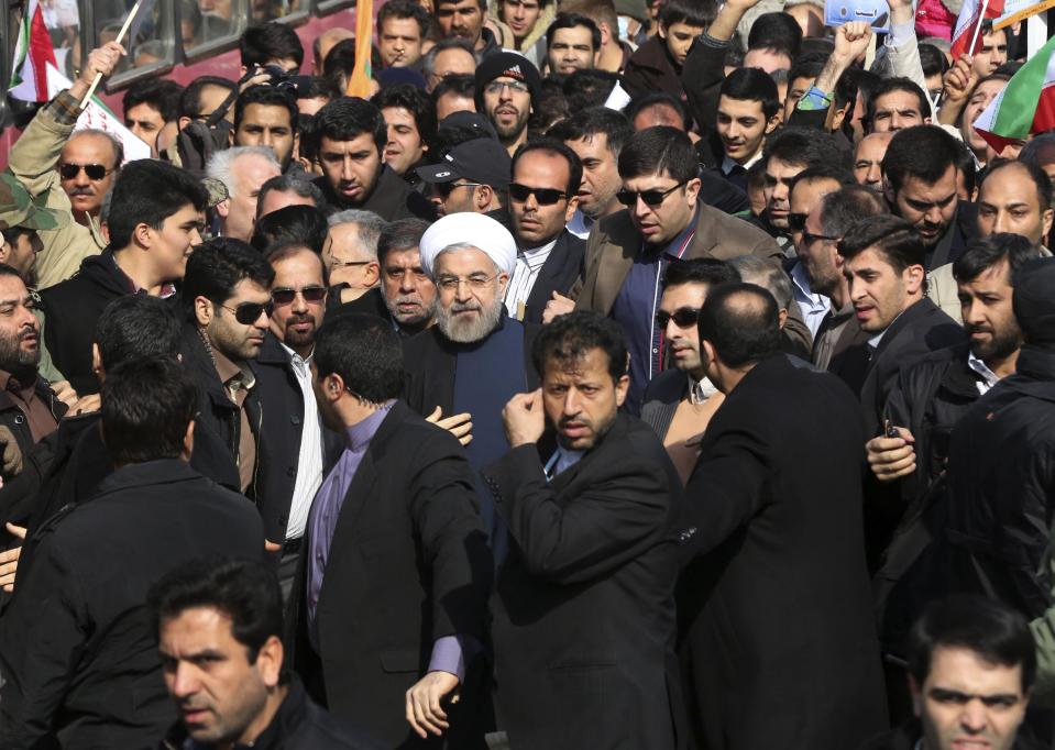 Escorted by his bodyguards, Iranian President Hassan Rouhani, center, waves to his well wishers as he attends an annual rally commemorating the anniversary of the 1979 Islamic revolution, in Tehran, Iran, Tuesday, Feb. 11, 2014. Rouhani on Tuesday called for "fair and constructive" nuclear talks with world powers as the nation marked the anniversary of the 1979 Islamic revolution with massive rallies, complete with anti-American and anti-Israeli chants. Tuesday marks the 35th anniversary of the revolution that toppled the pro-U.S. Shah Mohammad Reza Pahlavi and brought Islamists to power. (AP Photo/Vahid Salemi)