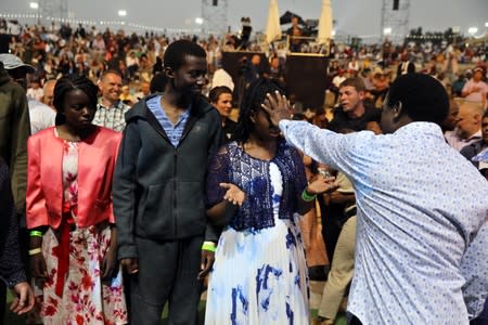 T.B. Joshua, a Nigerian evangelical preacher places his hand over the face of a woman as he leads a religious retreat on Mount Precipice, Nazareth